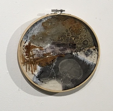 A wooden circle holds a collage of sewn fragments of textile prints. One shows an internal image of the upper intestines of the artist, the other is an x-ray profile of a head and shoulders. Images are connected with burlap, sections are died with rust.